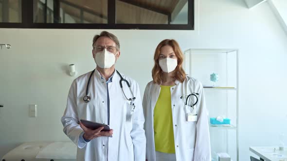 Confident doctors with protective face masks standing in practice