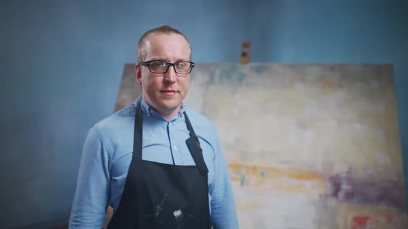 Slow Motion Portrait of an Adult Male Artist Standing Against the Background of a Large Canvas a Man