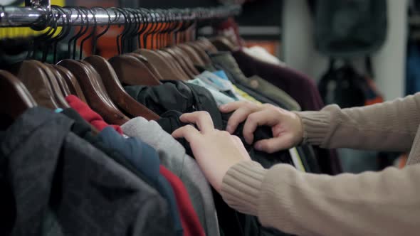Men Sweaters and Shirts in Different Colors on Hangers in a Retail Clothes Store Man Choose Hoodies