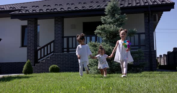 Little Girls Walk With Her Sister In The Courtyard Of The House