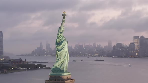 AERIAL: Circling Statue of Liberty Illuminated in Early Morning Light with Foggy New York City