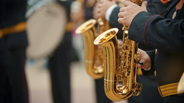 A Wind Instrument Parade - Men in Dark Costumes Playing Saxophone Outdoors - Military Music Festival