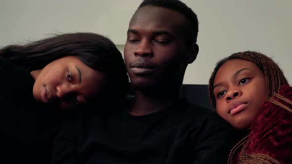 One African Man and Two African Woman Together Watch Television in Living Room - Closeup