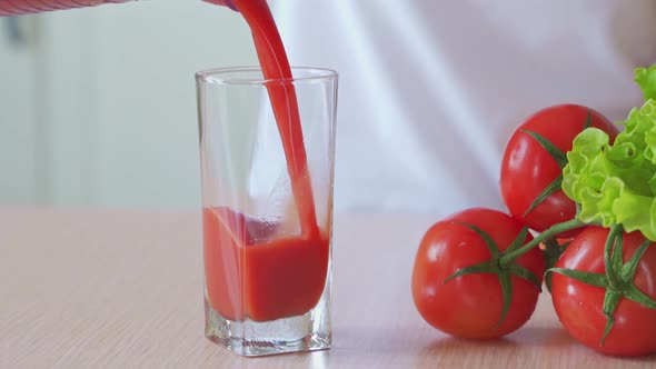 Tomato Juice Pouring From Jug Into a Glass.