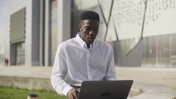 Online Video Chat By African Businessman Sitting on Bench