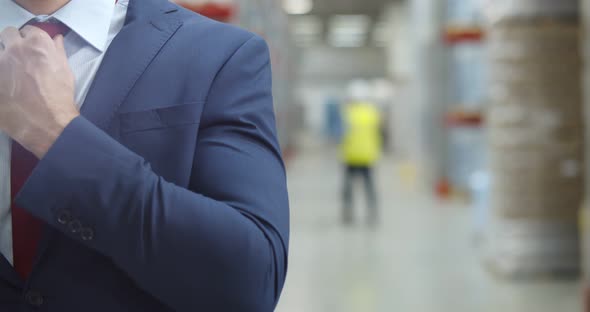 Cropped Shot of Businessman Adjusting Tie Standing in Warehouse