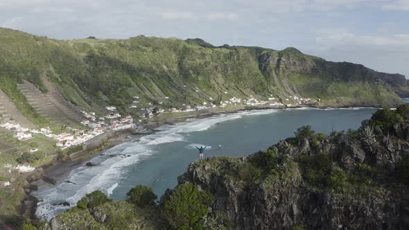 Aerial view of a person watching coastline on the cliff by the ocean.