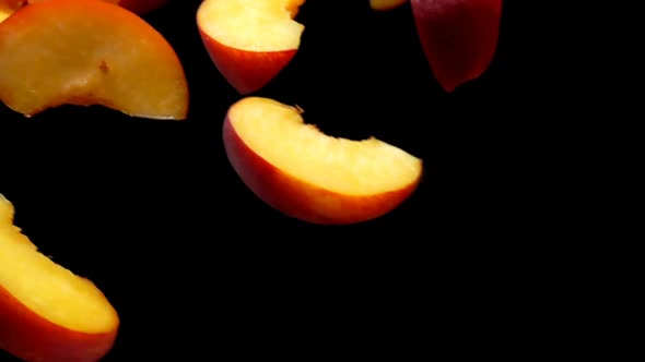 Fresh Peach Slices are Flying Diagonally on the Black Background