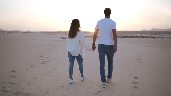 Backside Footage of Holding Hands Couple Walking in Romantic Relationship Under Sun and Blue Sky in