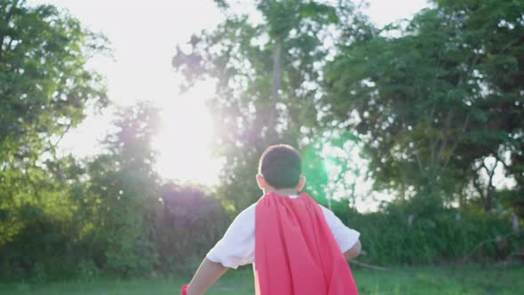 Back view of Asian boy holding sword and running in the park