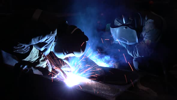 Welders welding metalwork in a factory