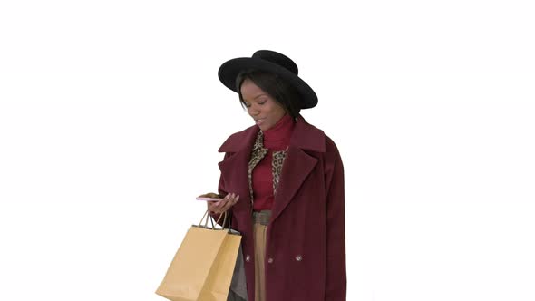 Smiling African American Fashion Girl in Coat and Black Hat Texting on Her Phone on White Background