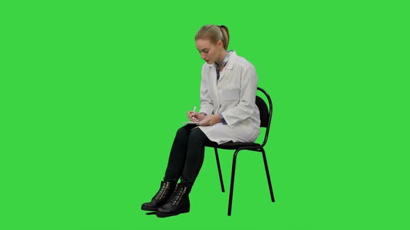 Female Doctor Writing Recipe for a Patient on a Green Screen, Chroma Key.