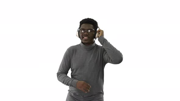 Smiling African American Man Holding Headphones with One Hand and Grooving To Music While Walking at