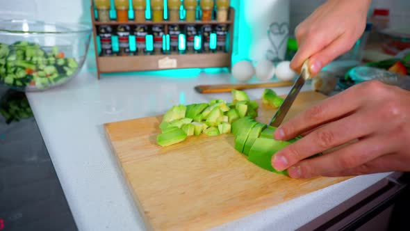 Men Hands Slice Avocados on a Wooden Board