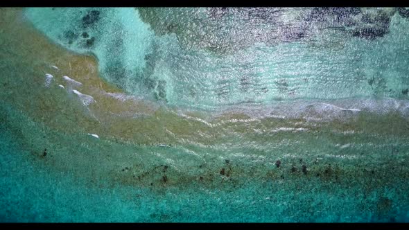 Aerial flying over sky of perfect coastline beach break by blue lagoon with white sandy background o