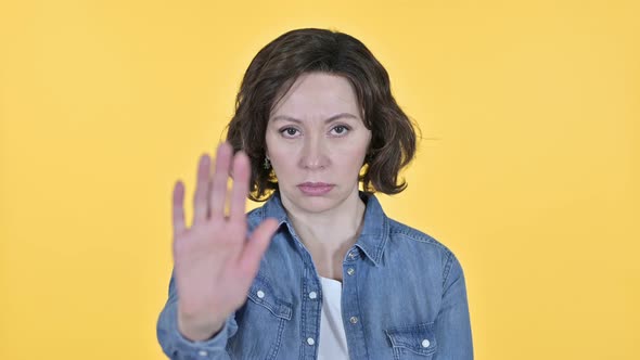 Stop Gesture By Old Woman on Yellow Background 