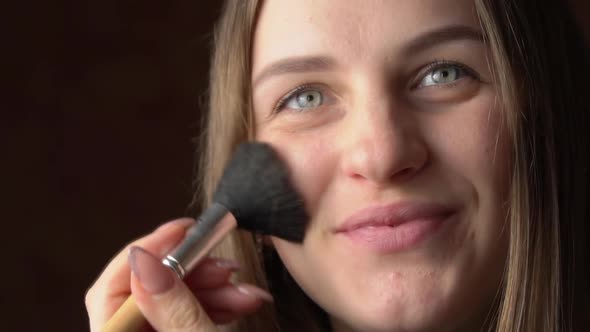 Face of a Beautiful Young Woman Applying Blush with a Brush on Her Face