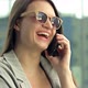 Cheerful Young Woman in Sunglasses Talking on the Phone While Standing on a City Street - VideoHive Item for Sale