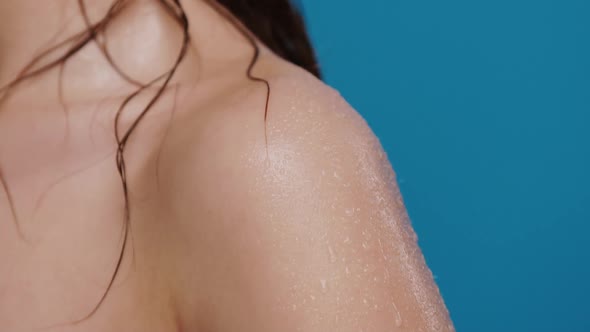 Close-up of Water Splashes Falling Down From Wet Woman Shoulder Isolated on Blue