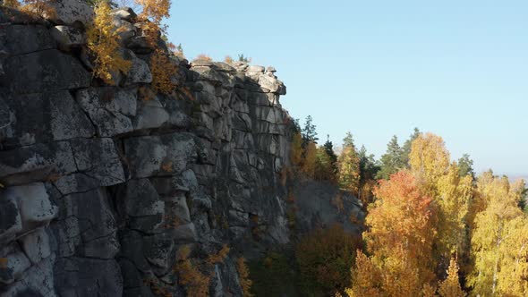 Aerial View of a Cliff Surrounded By a Colorful Autumn Forest at Sunset