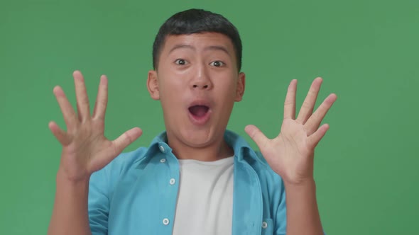 Shocked Young Asian Boy Grabbing Her Head While Saying Wow On Green Screen Background In The Studio