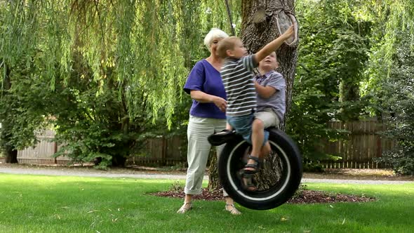 Woman pushing grandchildren on swing