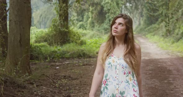 Young beautiful woman with a white dress walking in a green forest