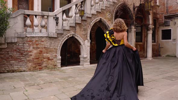 Model in Carnival Dress Walks Along Empty Italian Courtyard
