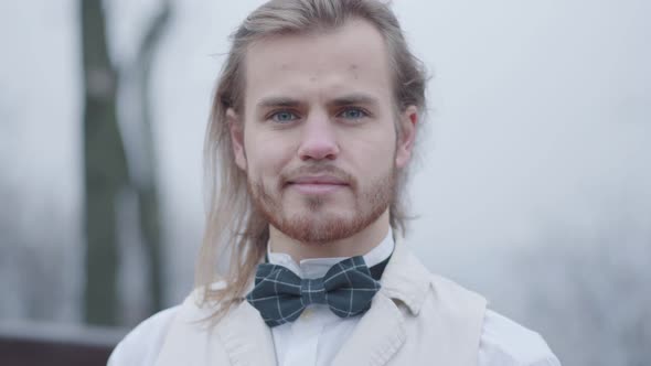 Close-up Face of Stylish Caucasian Man in White Shirt and Plaid Bow Tie Looking at Camera