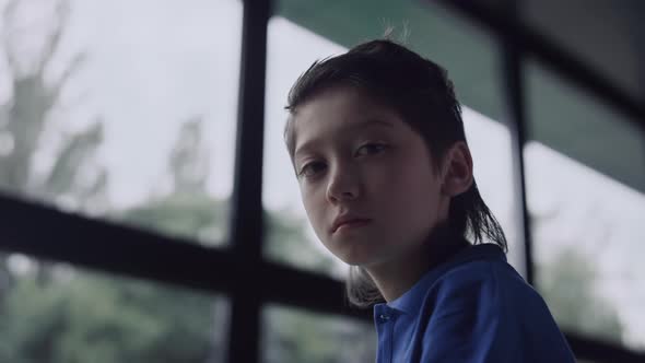 Depressed Boy Watching Out Window in School Close Up