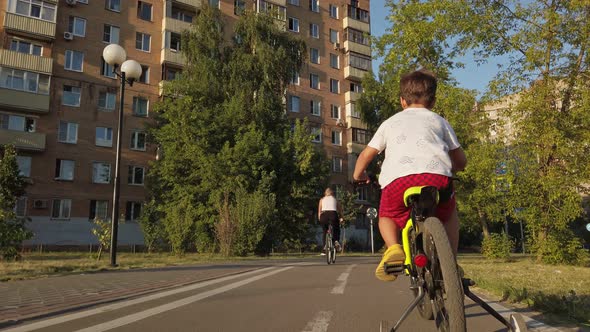 a Little Boy Famously Rides a Children's Bike on a Bicycle Path in the Summer