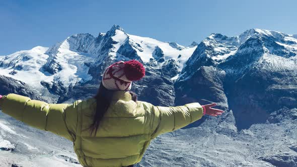 Back View of a Woman Embracing Fresh Air with Mountains Covered By Snow in Summer Season