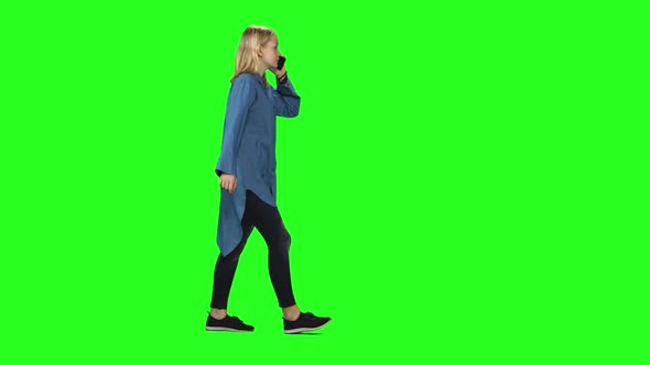 Blonde Teenager Girl Calmly Walking and Talking on the Mobile Phone on Green Screen. Chroma Key