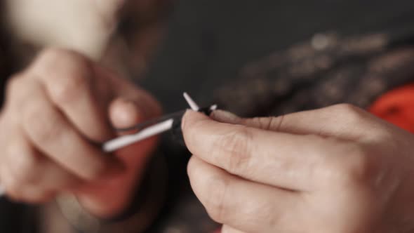 Close up of woman's hands knitting with black wool and needle crafts. 4k footage of knit work tie-up