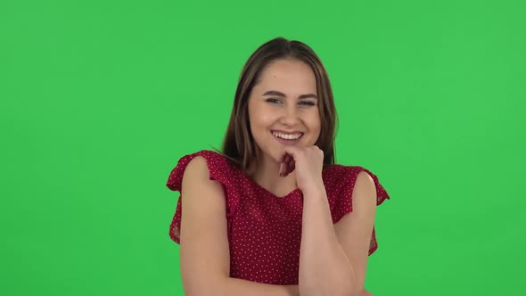 Portrait of Tender Girl in Red Dress Communicates with Someone in a Friendly Manner. Green Screen