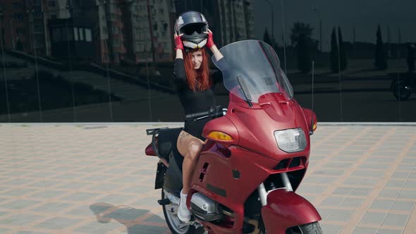 Young woman on the motorcycle. Happy biker wearing an helmet sitting on her motorbike
