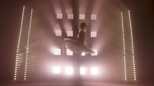 Diligent Young Graceful Ballerina Dancing Elements of Classical Ballet in the Dark with Light and