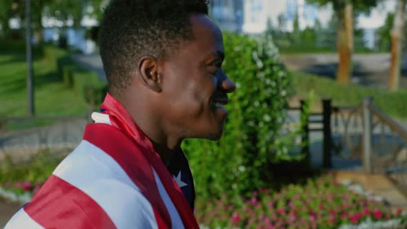 Side View Smiling Afroamerican Man Walking Street with American Flag on Back