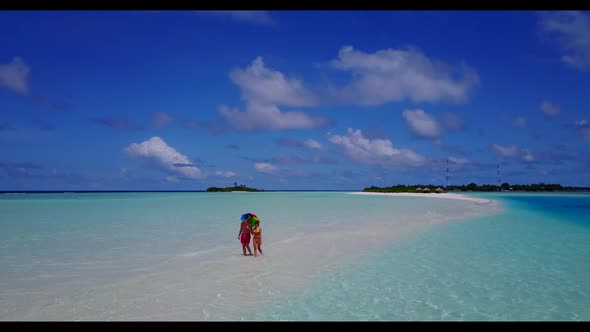 Man and woman posing on marine coast beach vacation by aqua blue sea with white sandy background of 