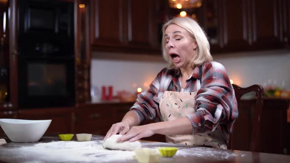 Side Angle View of Focused Young Caucasian Woman Kneading Dough and Sneezing