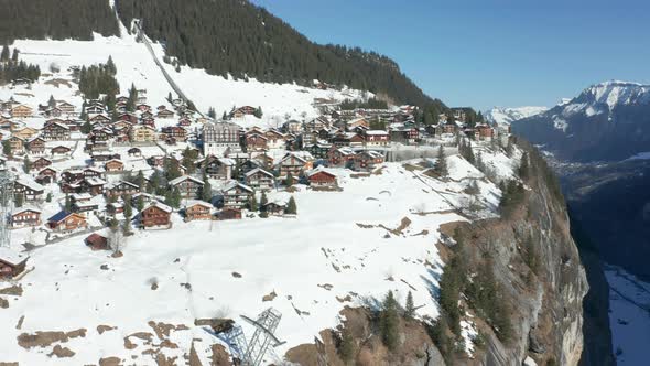 Paraglider jumping of edge of mountain near beautiful Swiss town