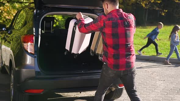 Handsome Bearded Modern Man Putting Into Car's Trunk Suitcases and Boxes During Moving Into New Home