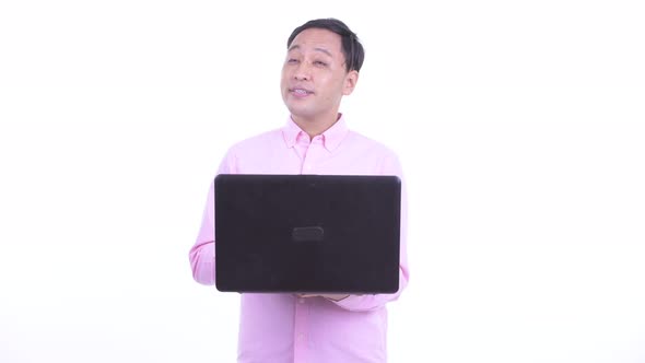 Happy Japanese Businessman Thinking While Using Laptop