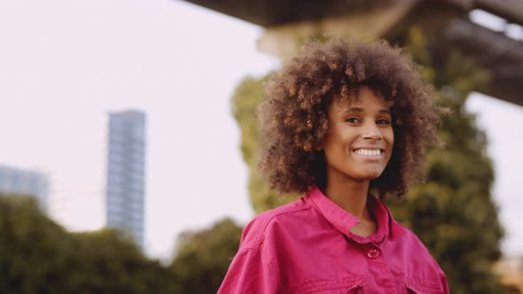 Smiling Young Woman With Afro Hair In Bright Pink Fashion