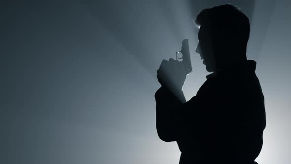 Silhouette Male Shooter Aiming Pistol in Darkness