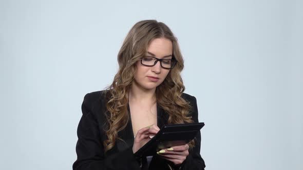 Woman Office Worker Makes Calculations on a Calculator Over Gray Background at Studio, Slow Motion