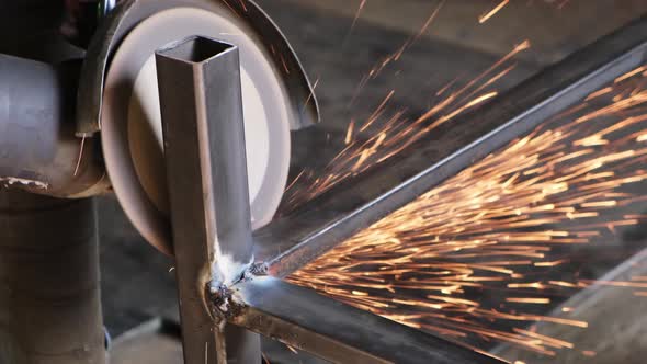 Sparks fly from disc of grinder in different directions during processing of welding seams