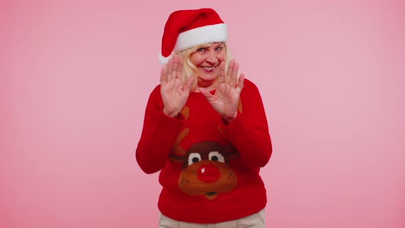 Grandmother Woman in Christmas Sweater with Deers Waves Hand Palm in Hello Gesture Welcomes Someone