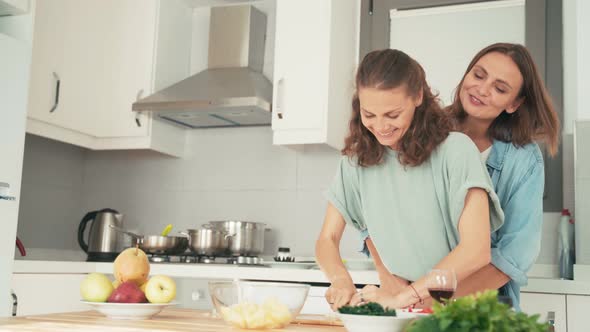 Young Lesbian Couple Dancing and Having Fun While Cooking in the Bright Kitchen.